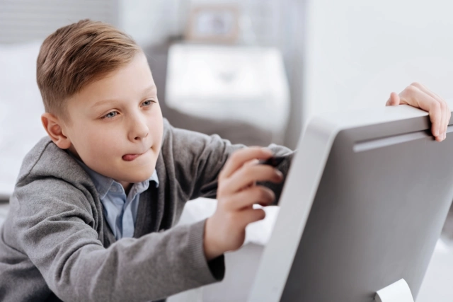 Gyerek monitort néz átéléssel, a nyelve kilóg